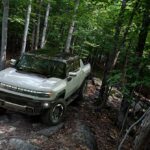 GMC Hummer EV driving through a forest